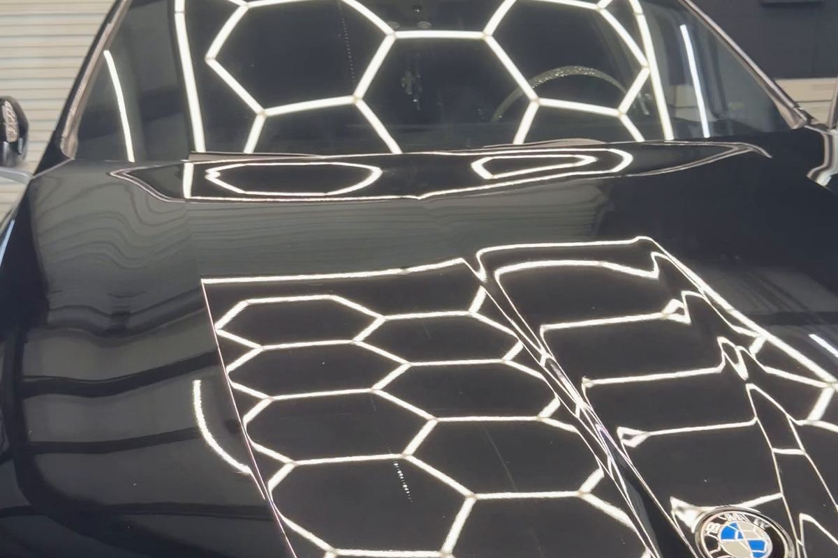 Black BMW hood and grille with a mirror-like gloss reflecting hex lights