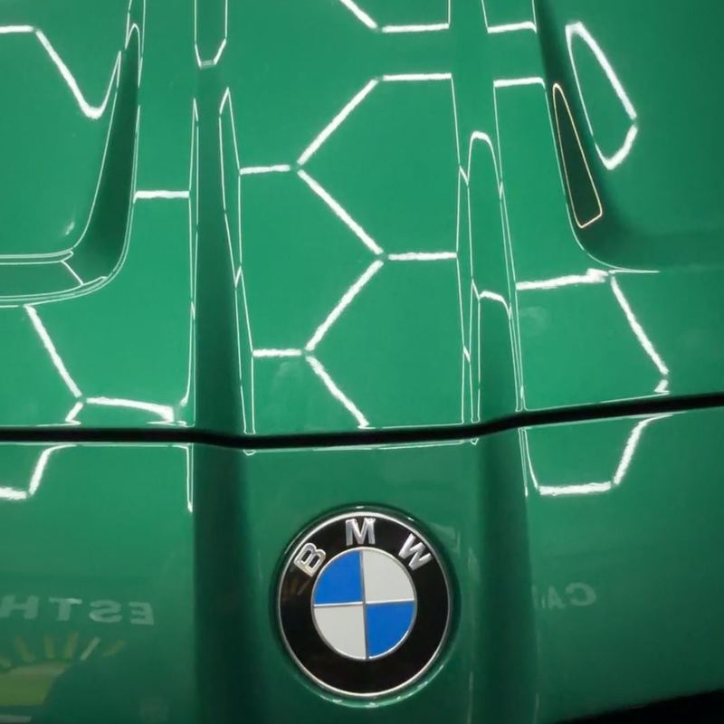 Green BMW M4 hood with a high-gloss finish reflecting hex lights